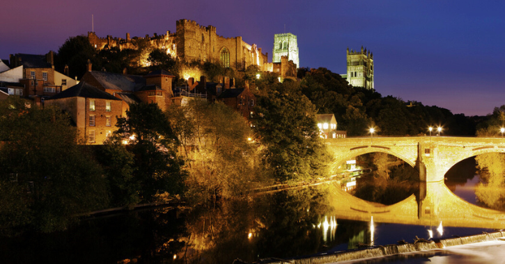 View of Durham City with cathedral and castle overlooking River Wear at night time.